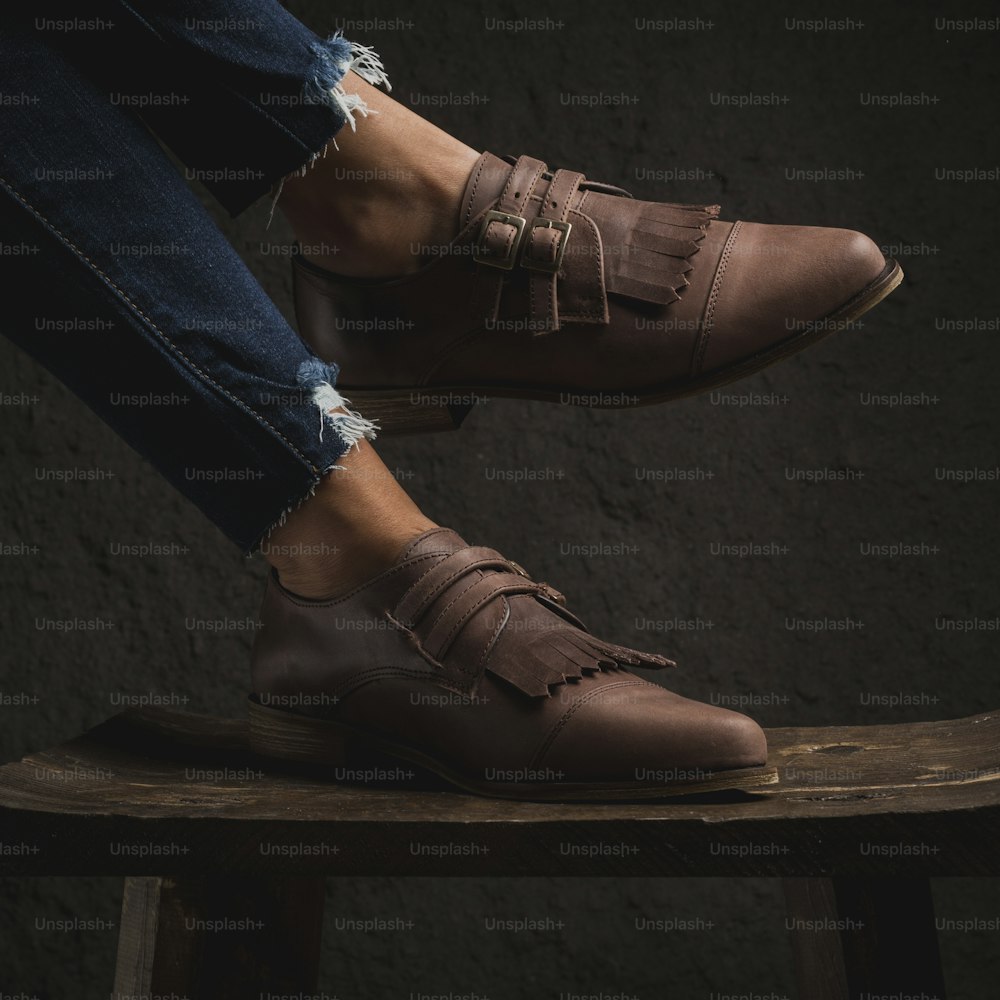 a person sitting on a stool wearing brown shoes