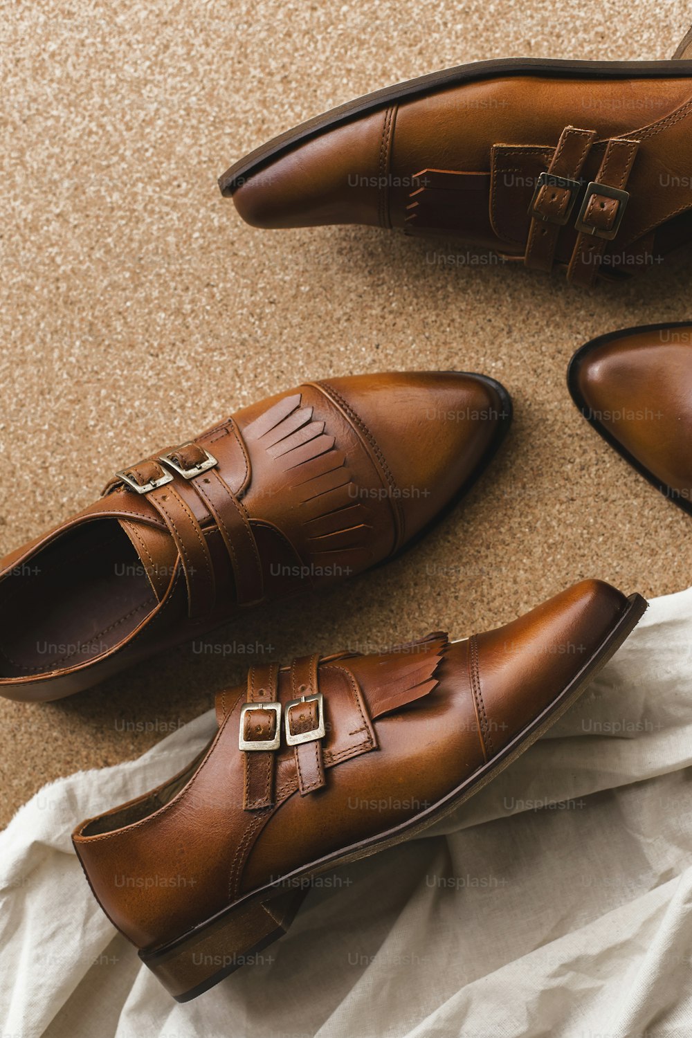 a pair of brown shoes sitting on top of a white sheet