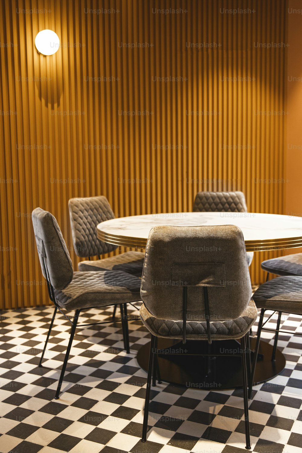 uma sala de jantar com piso quadriculado e uma mesa redonda