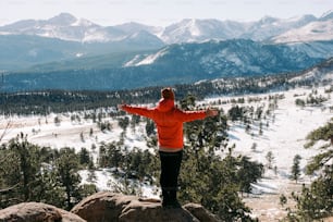 Una persona parada en la cima de una montaña con los brazos extendidos