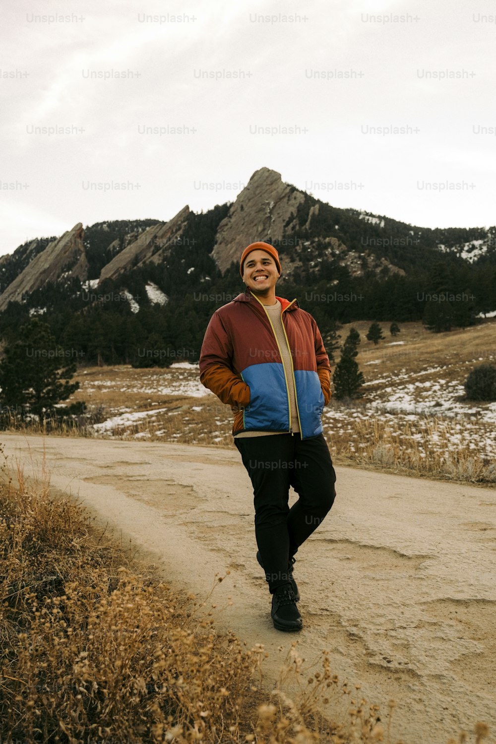a man standing on a dirt road in front of a mountain
