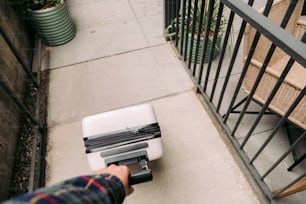 une personne pousse une valise dans les escaliers