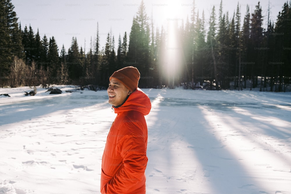 Un uomo in una giacca arancione in piedi nella neve