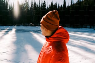 Una persona in una giacca arancione in piedi nella neve
