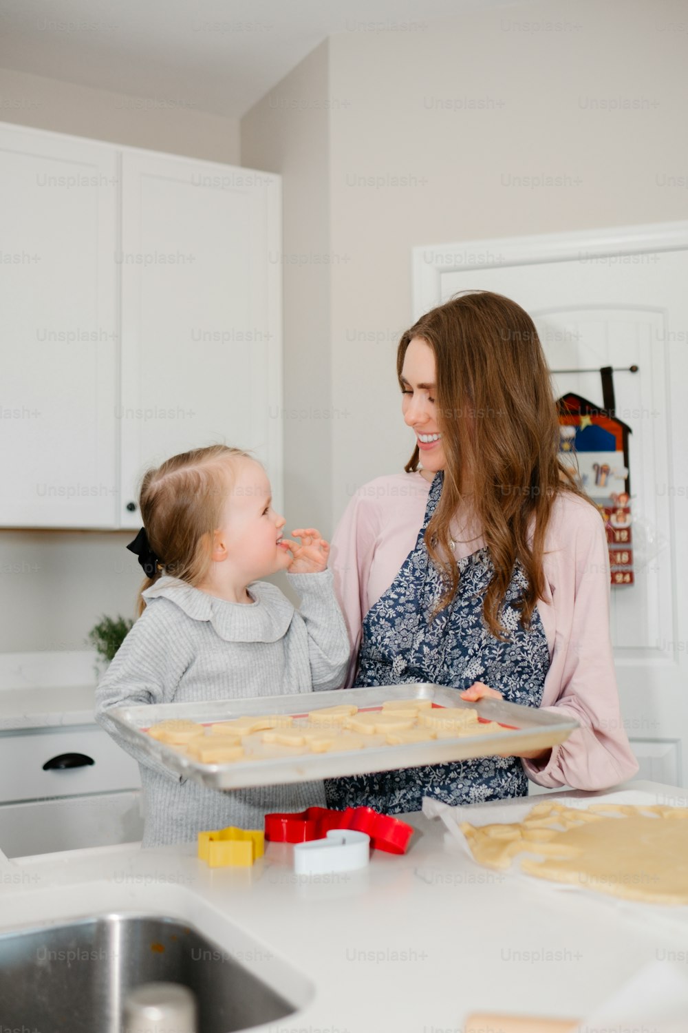 Una donna che tiene un vassoio di biscotti accanto a una bambina