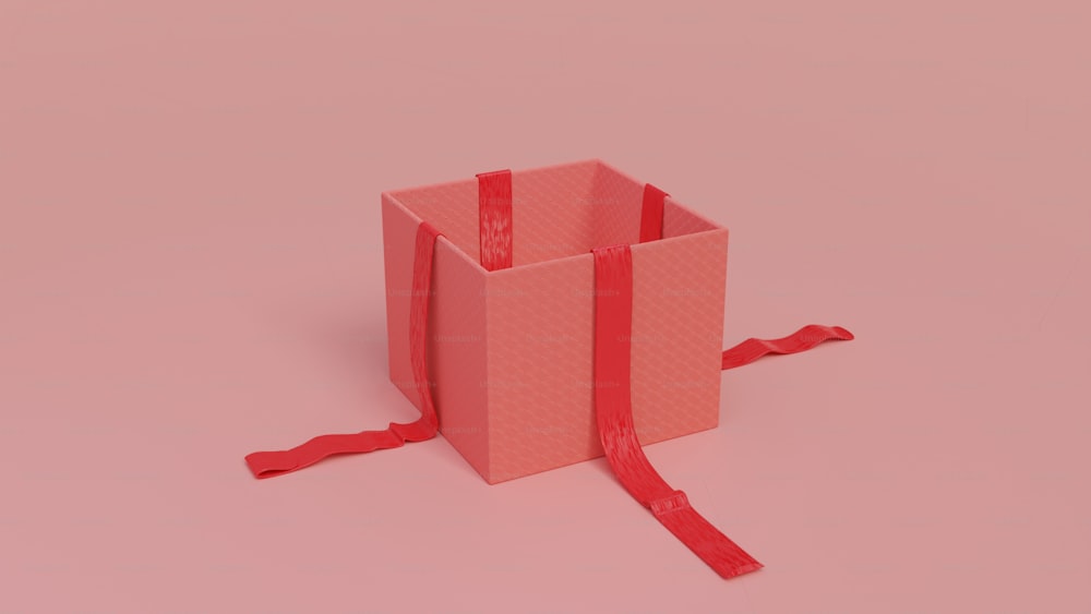 una scatola rosa con un nastro rosso legato intorno ad essa