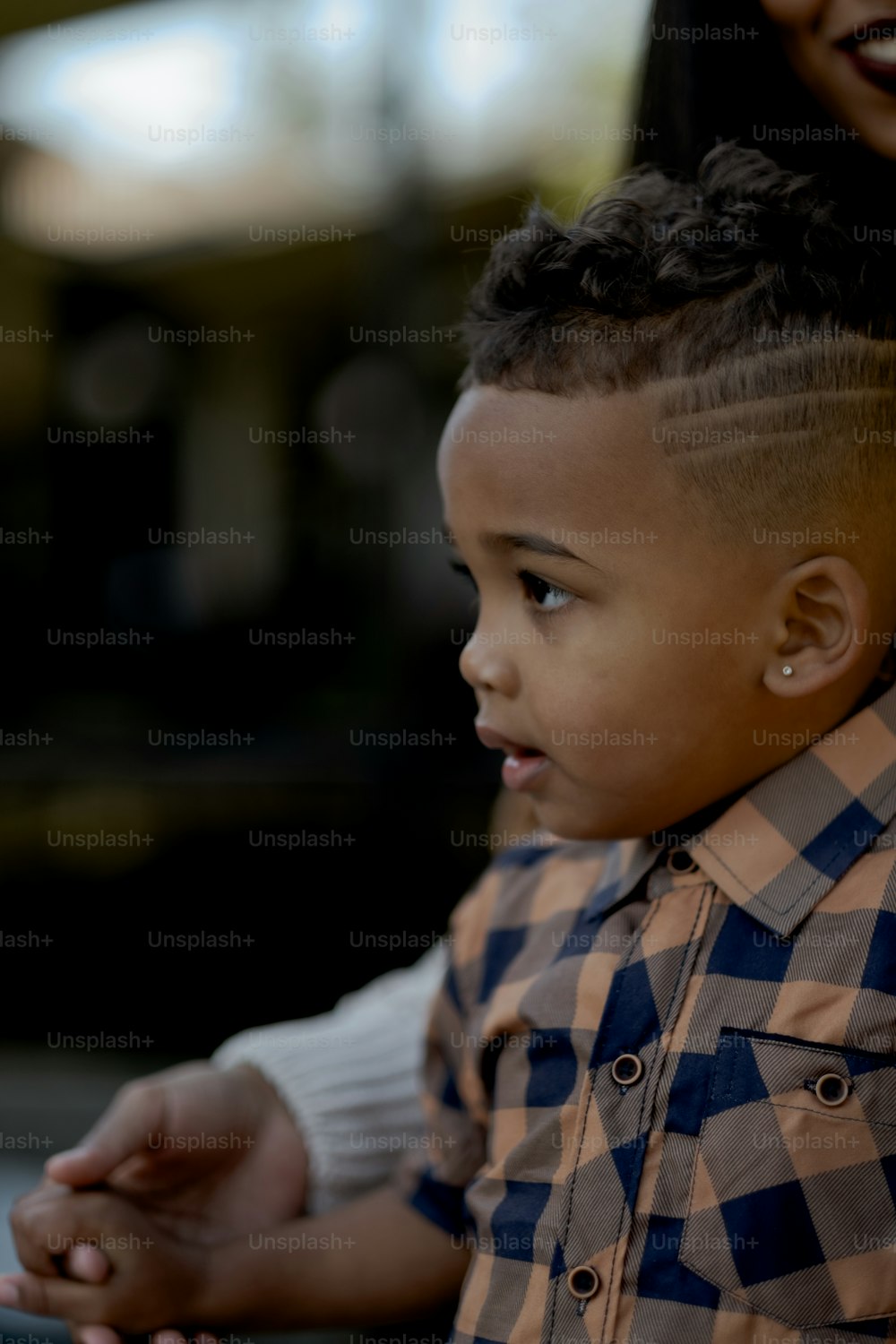 a little boy with a mohawk sitting next to a woman