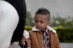 a little boy is holding a flower in his hand