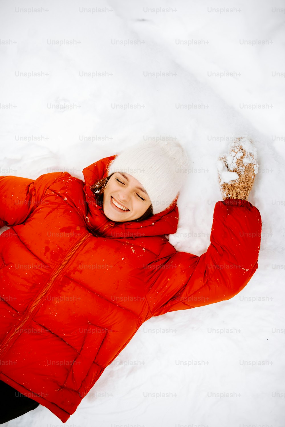 uma mulher em uma jaqueta vermelha deitada na neve
