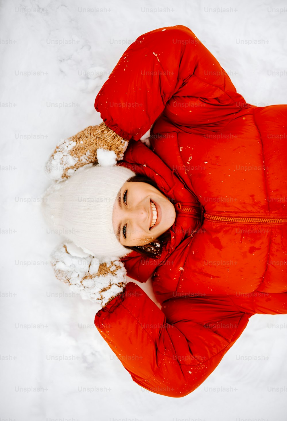 Una donna in una giacca rossa che giace nella neve