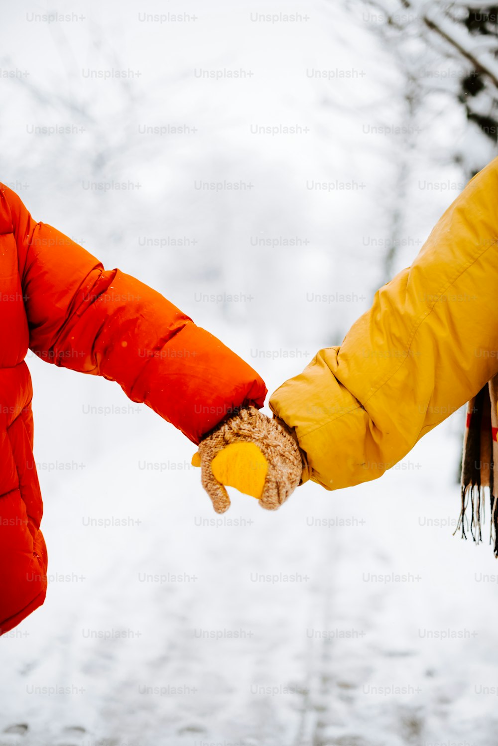 two people holding hands while walking in the snow