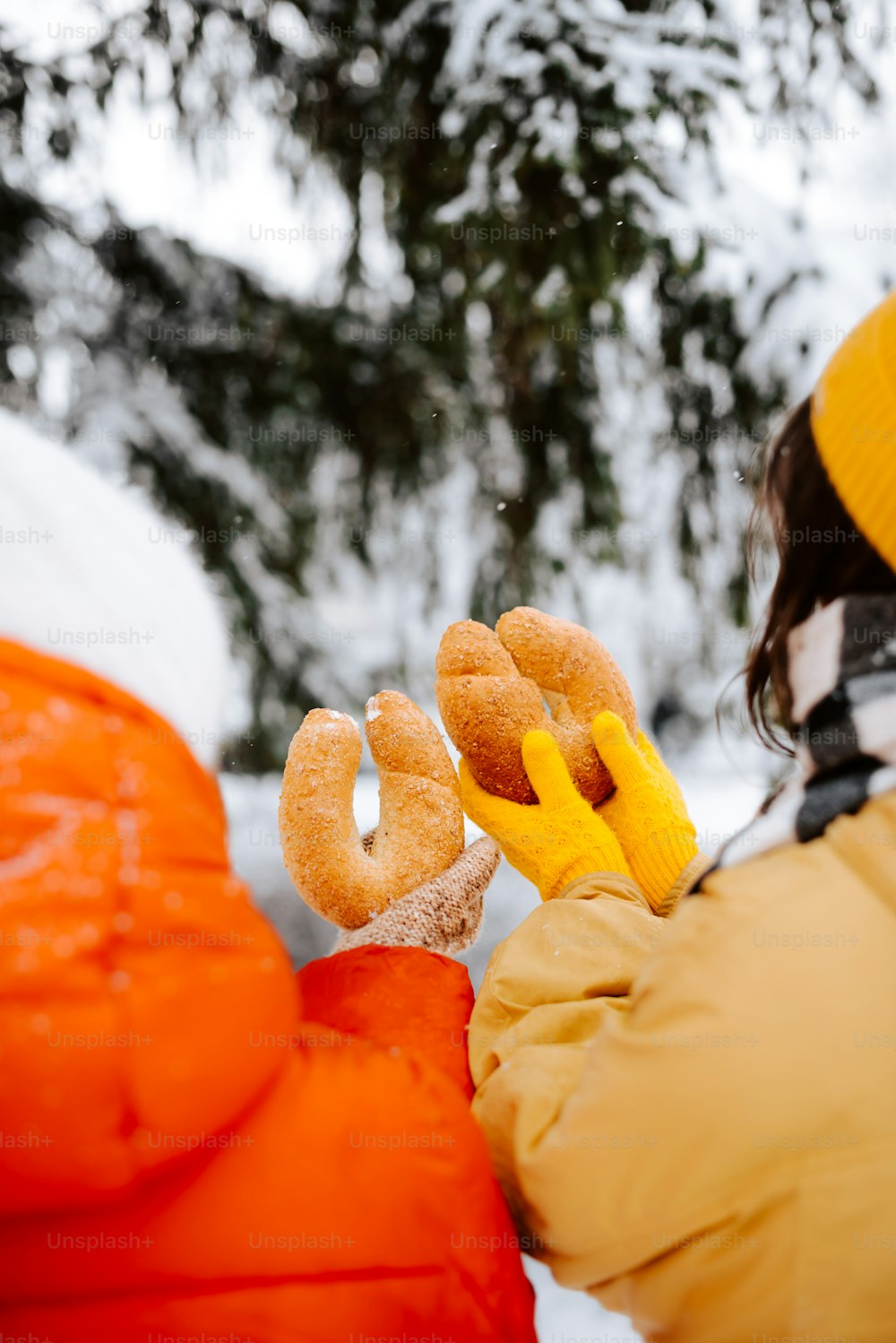 a person holding doughnuts in their hands in the snow