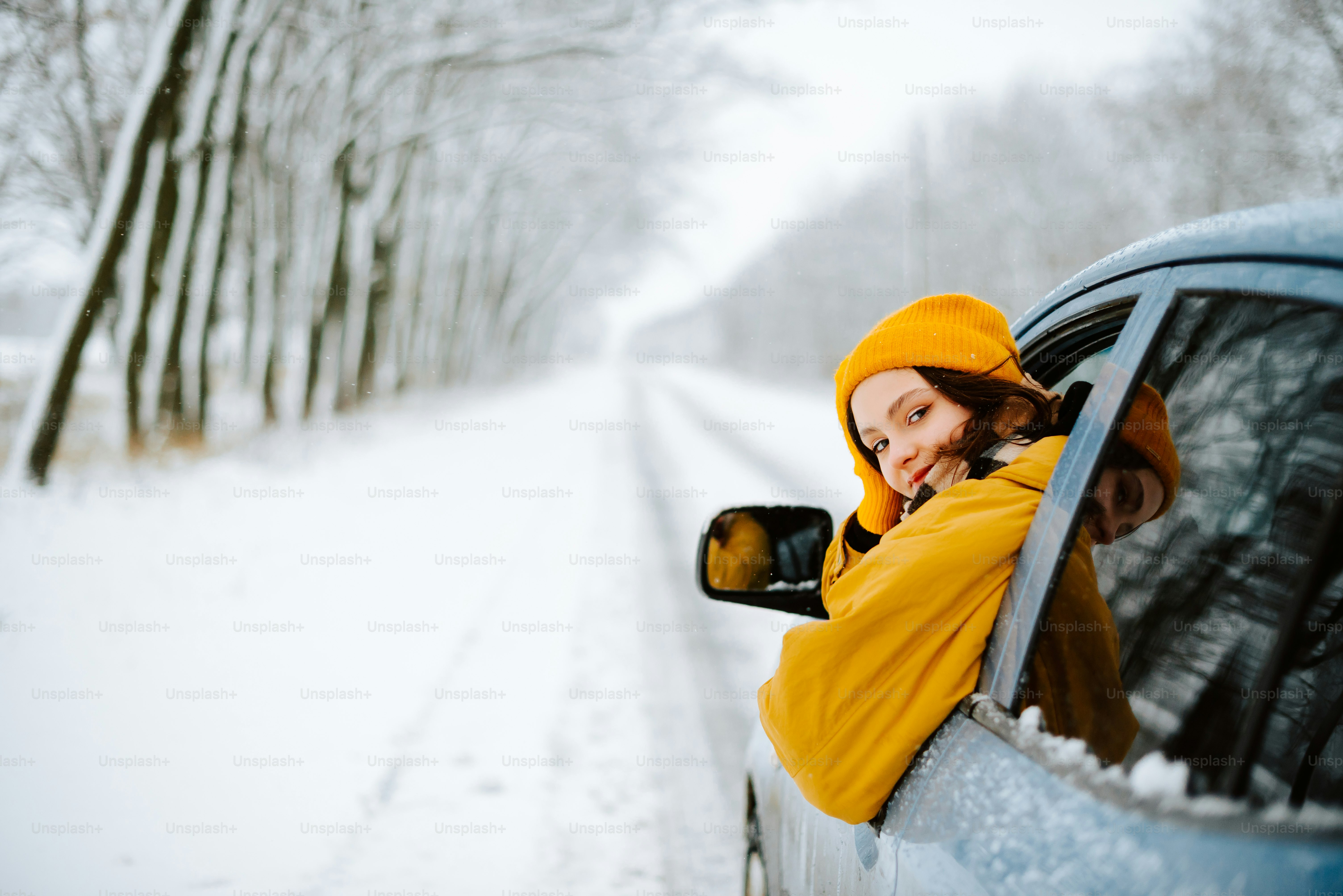 a woman in a yellow jacket leaning out of a car window