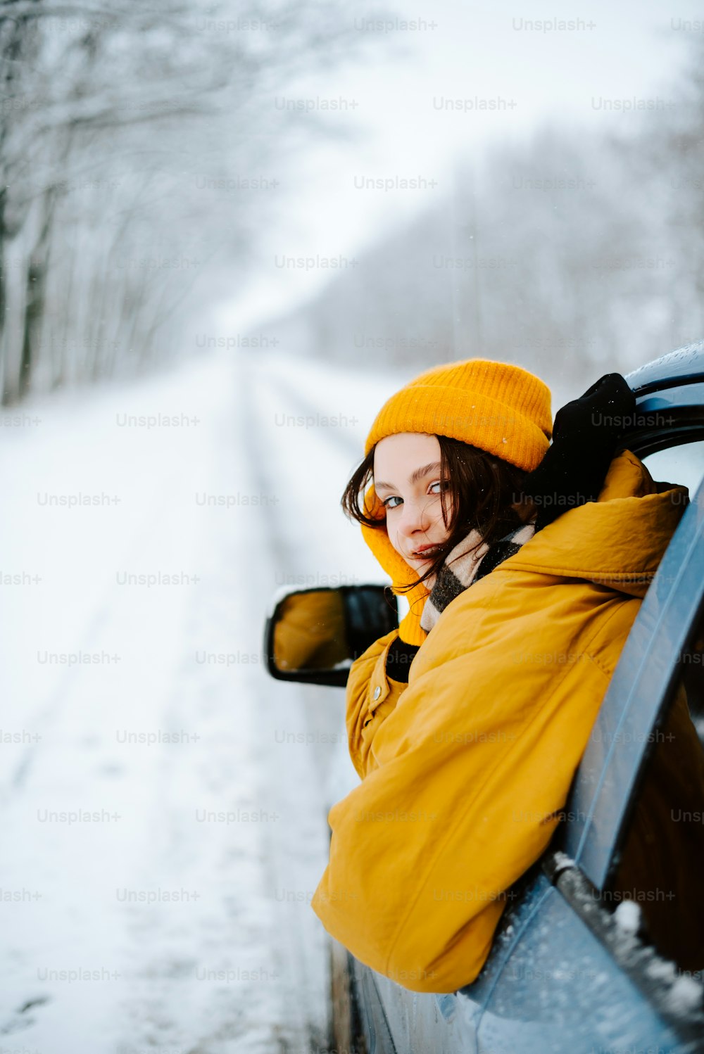a woman in a yellow jacket leaning out of a car window