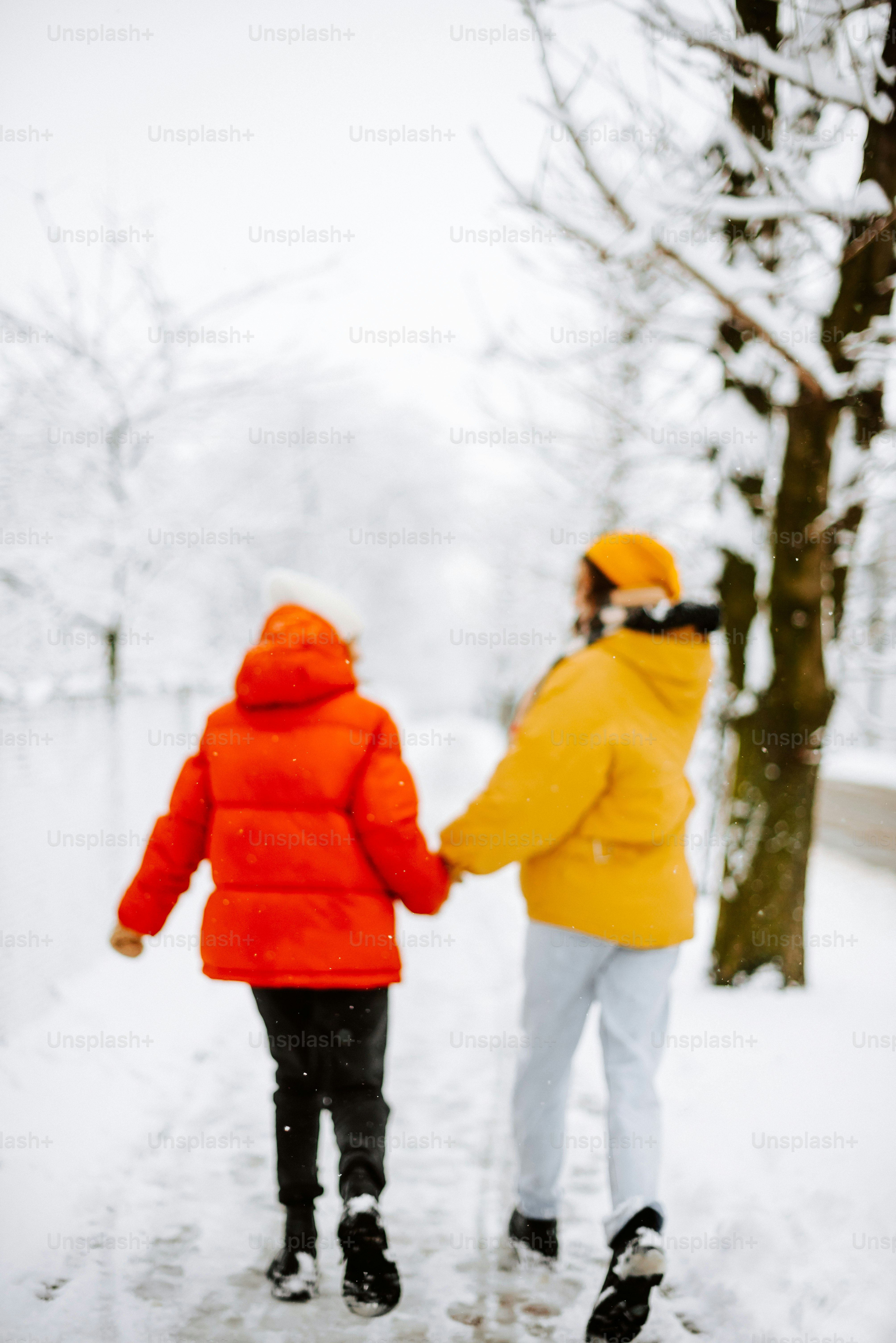 two people walking in the snow holding hands