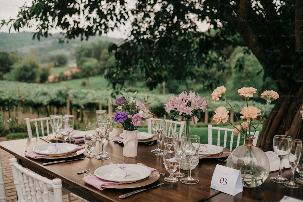 a wooden table topped with white plates and glasses