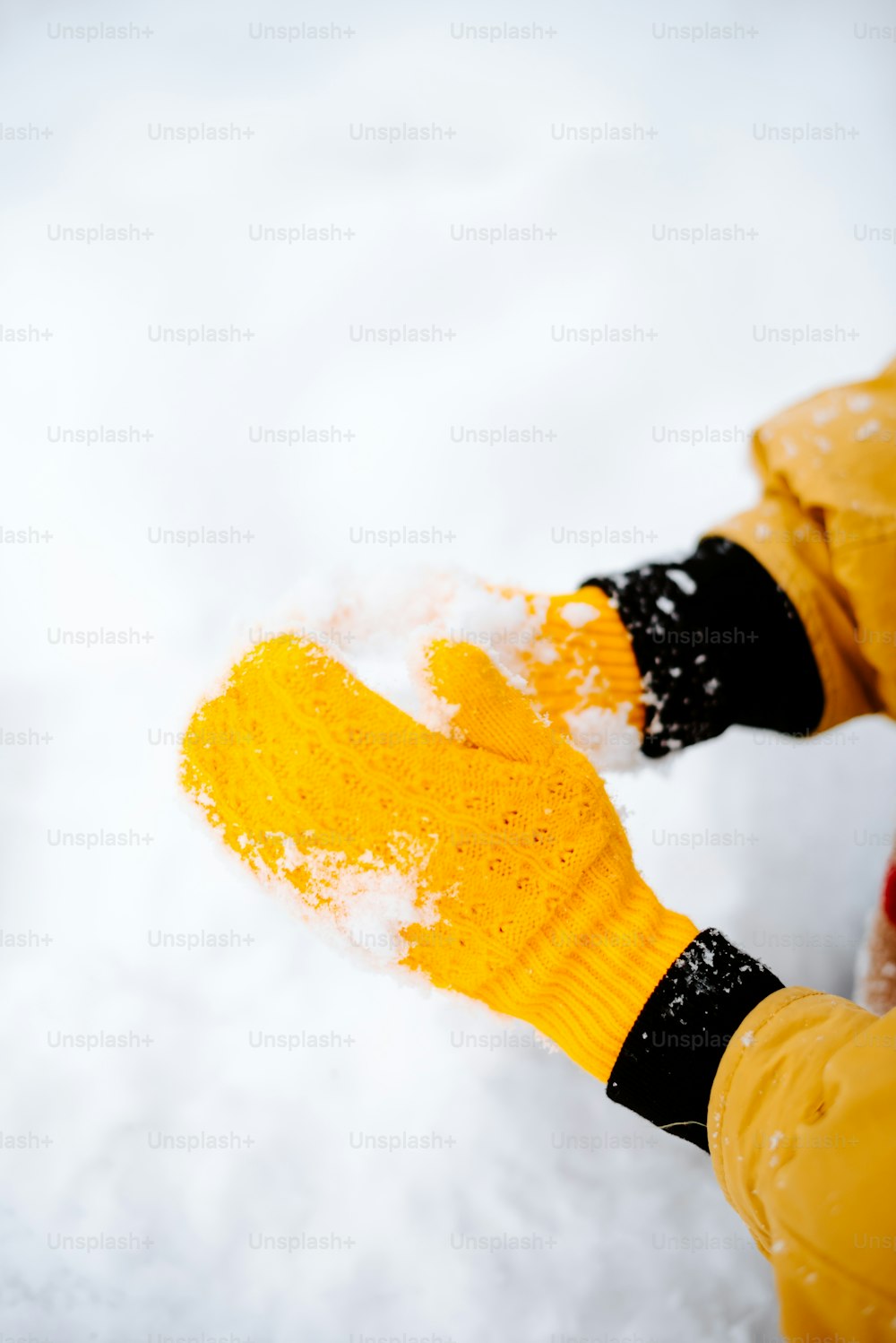 a person wearing yellow mittens standing in the snow