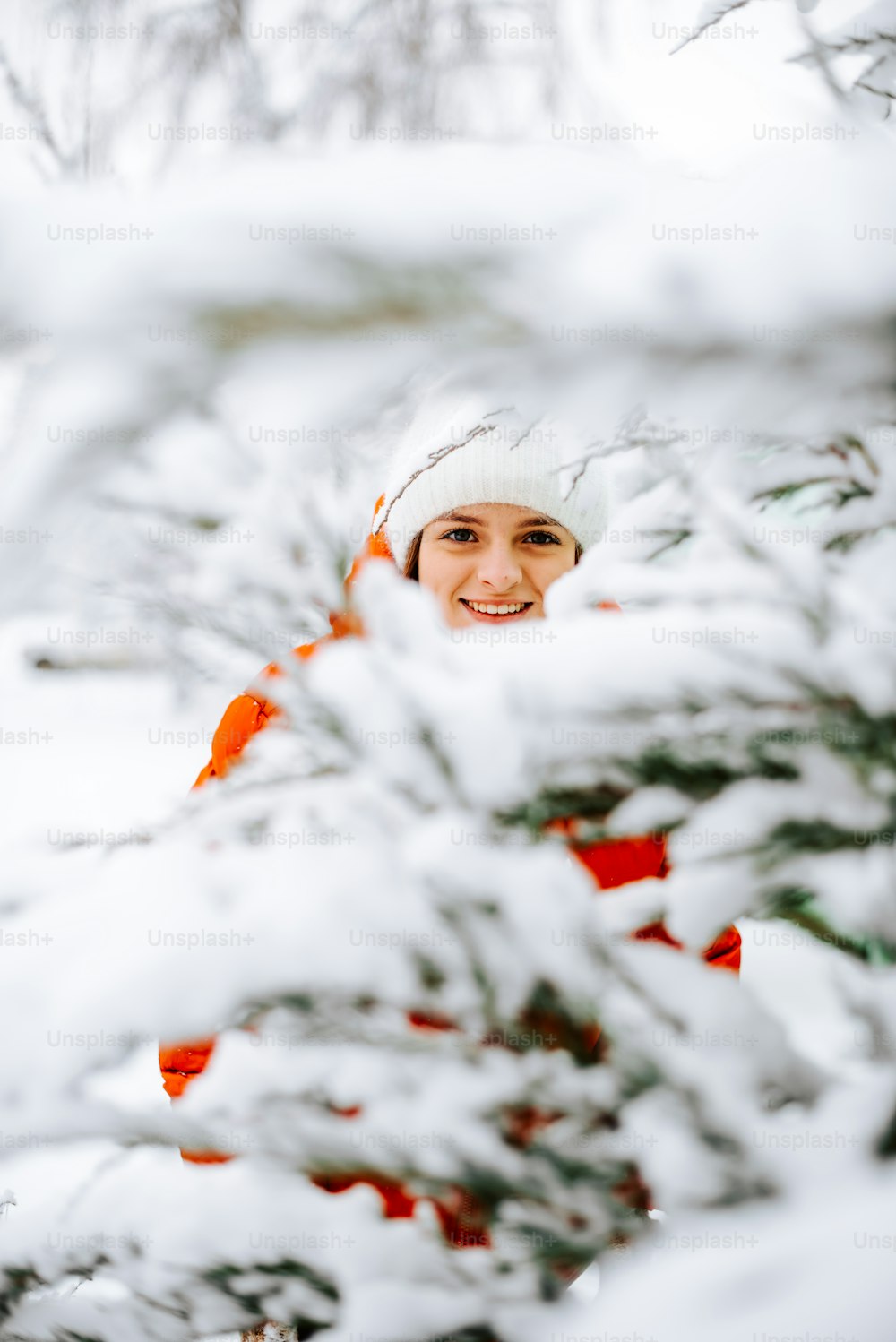 Eine Frau mit weißem Hut und roter Jacke im Schnee