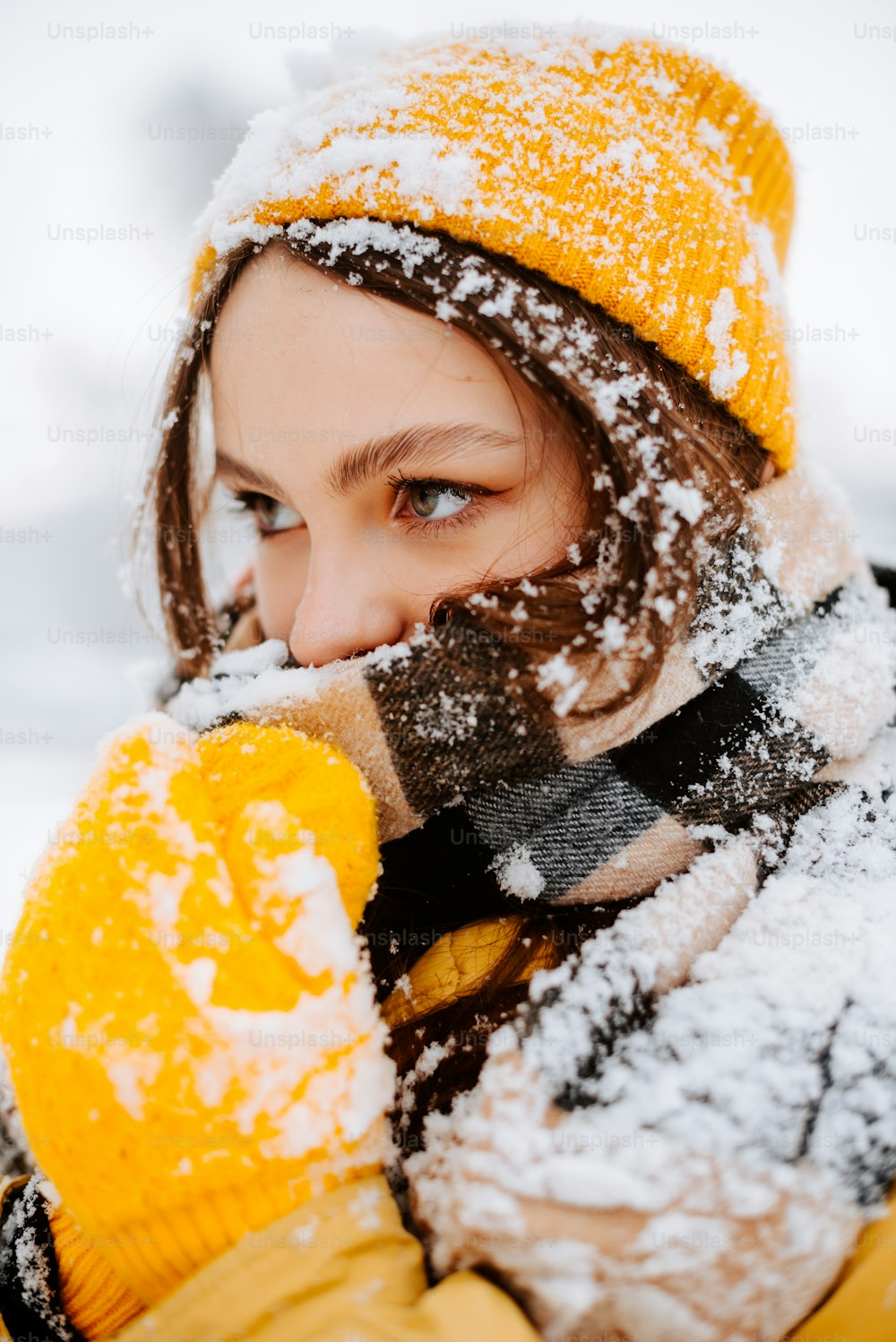 a woman wearing a yellow hat and scarf covered in snow