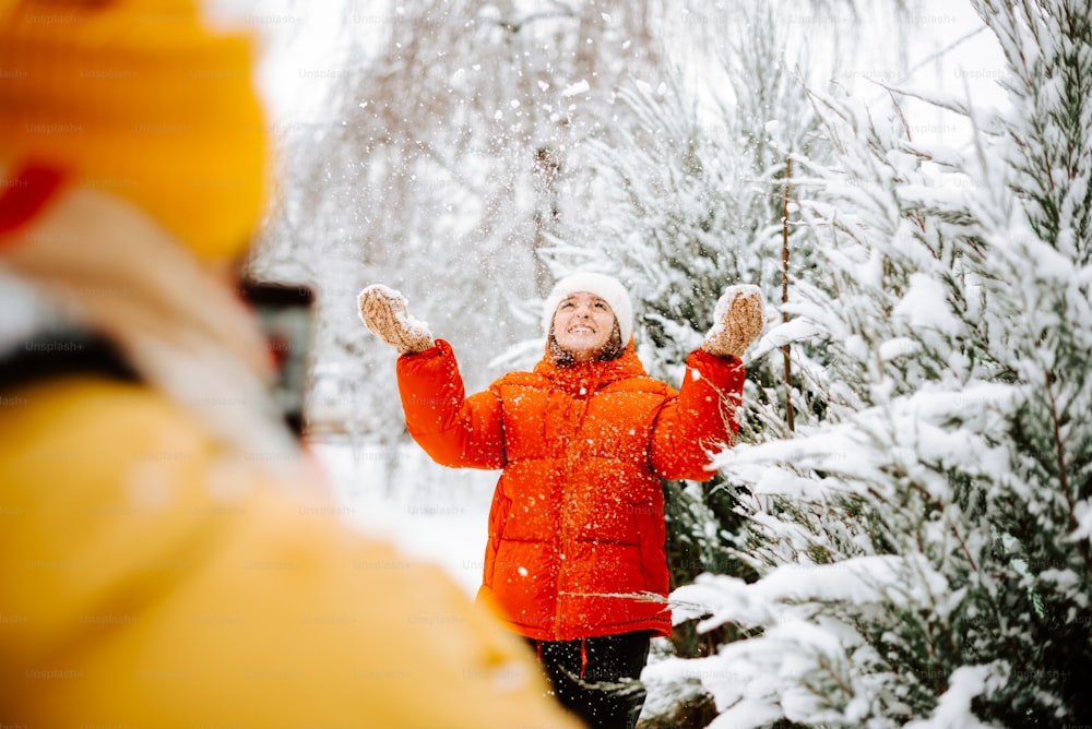 uma mulher em pé na frente de uma árvore nevada