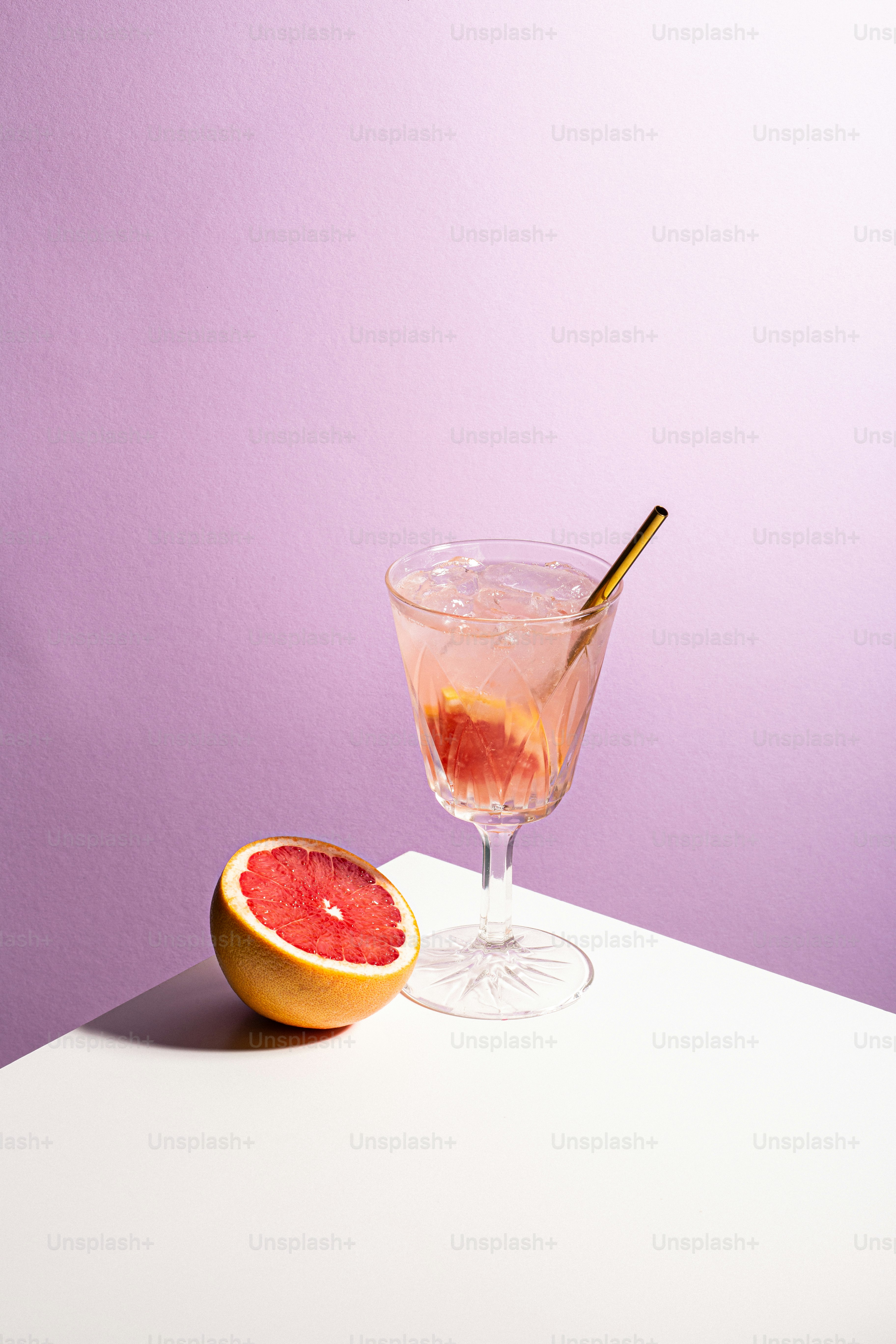 A grapefruit drink with a slice of grapefruit and a reusable straw