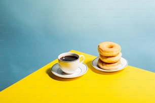 a stack of doughnuts next to a cup of coffee