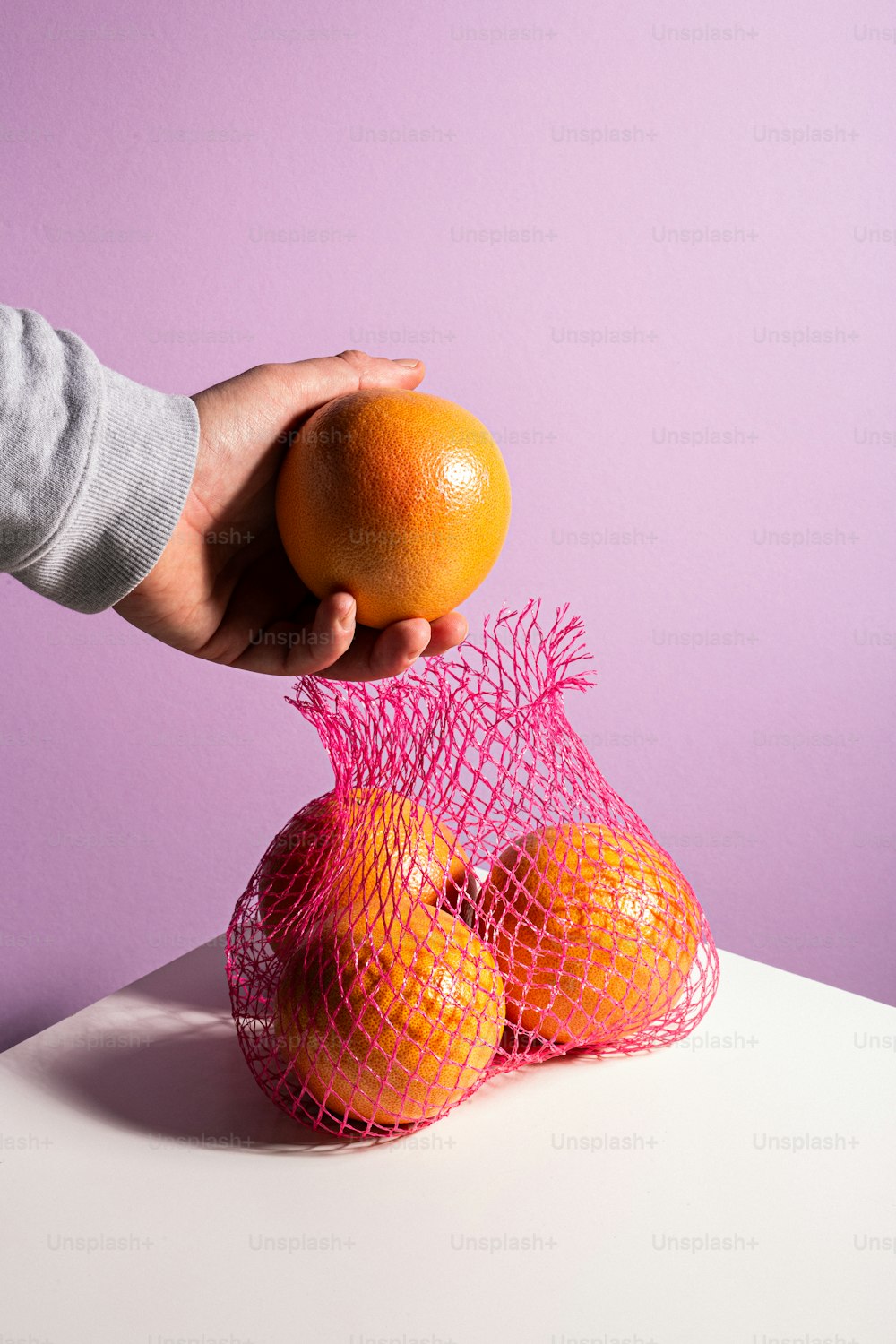 eine Person, die eine Tüte Orangen auf einem Tisch hält