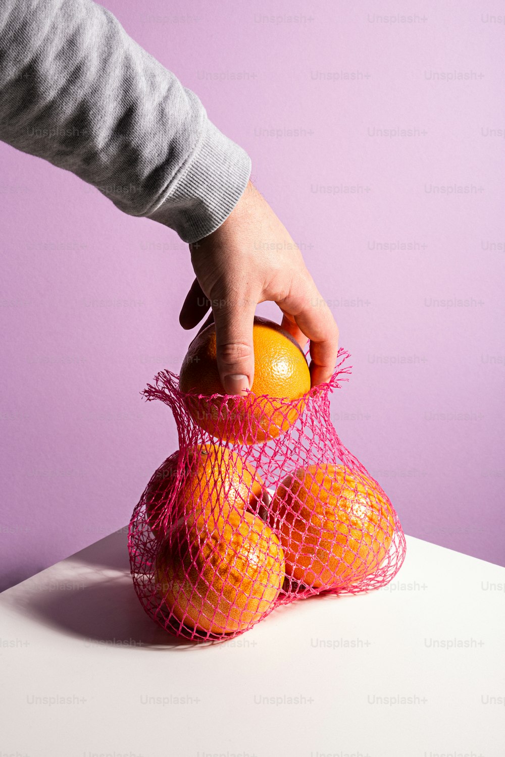 a person holding a bag of oranges on top of a table