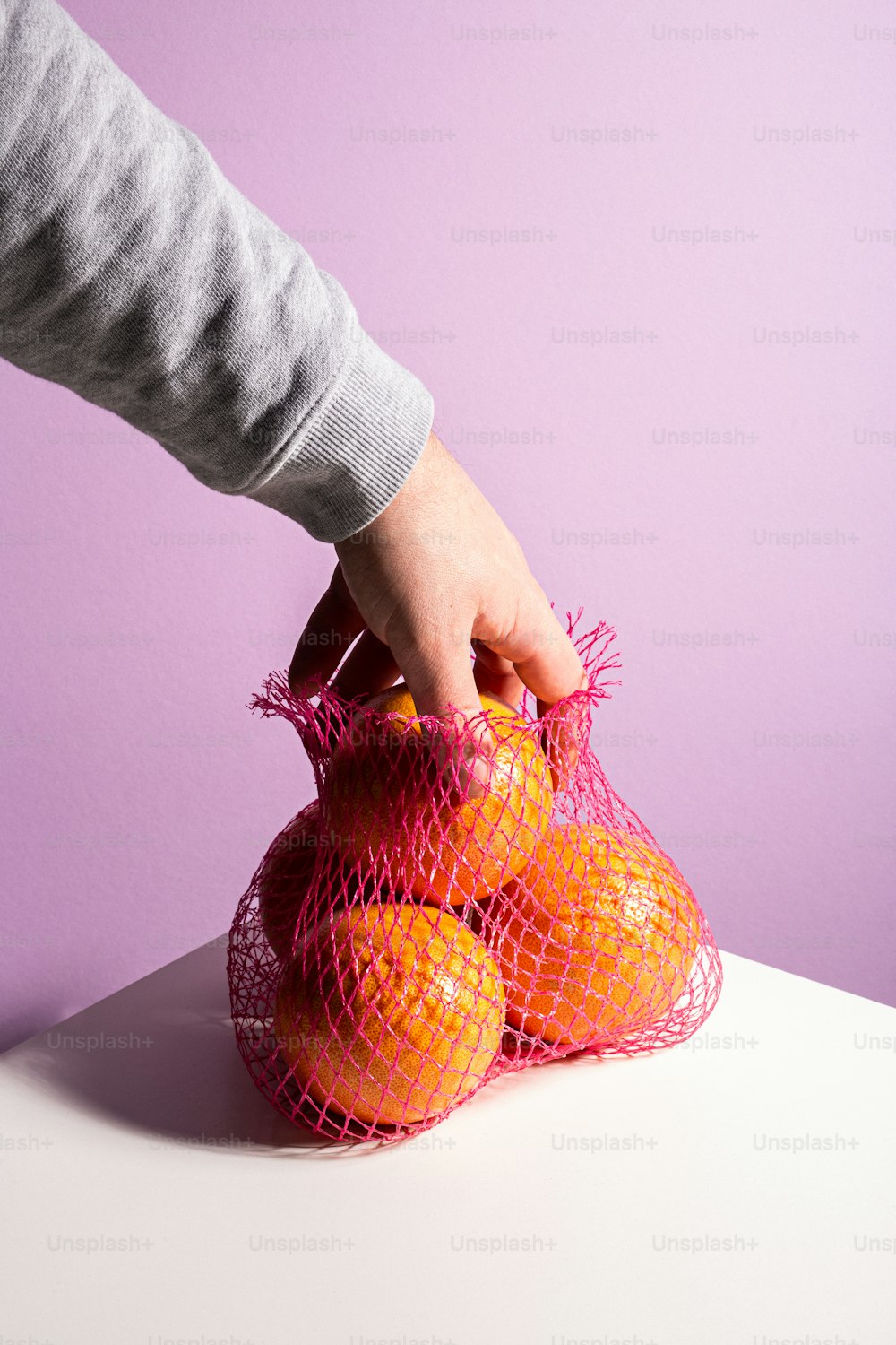a person holding a bag of oranges on a table