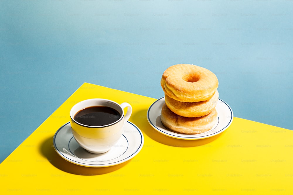 a stack of doughnuts next to a cup of coffee