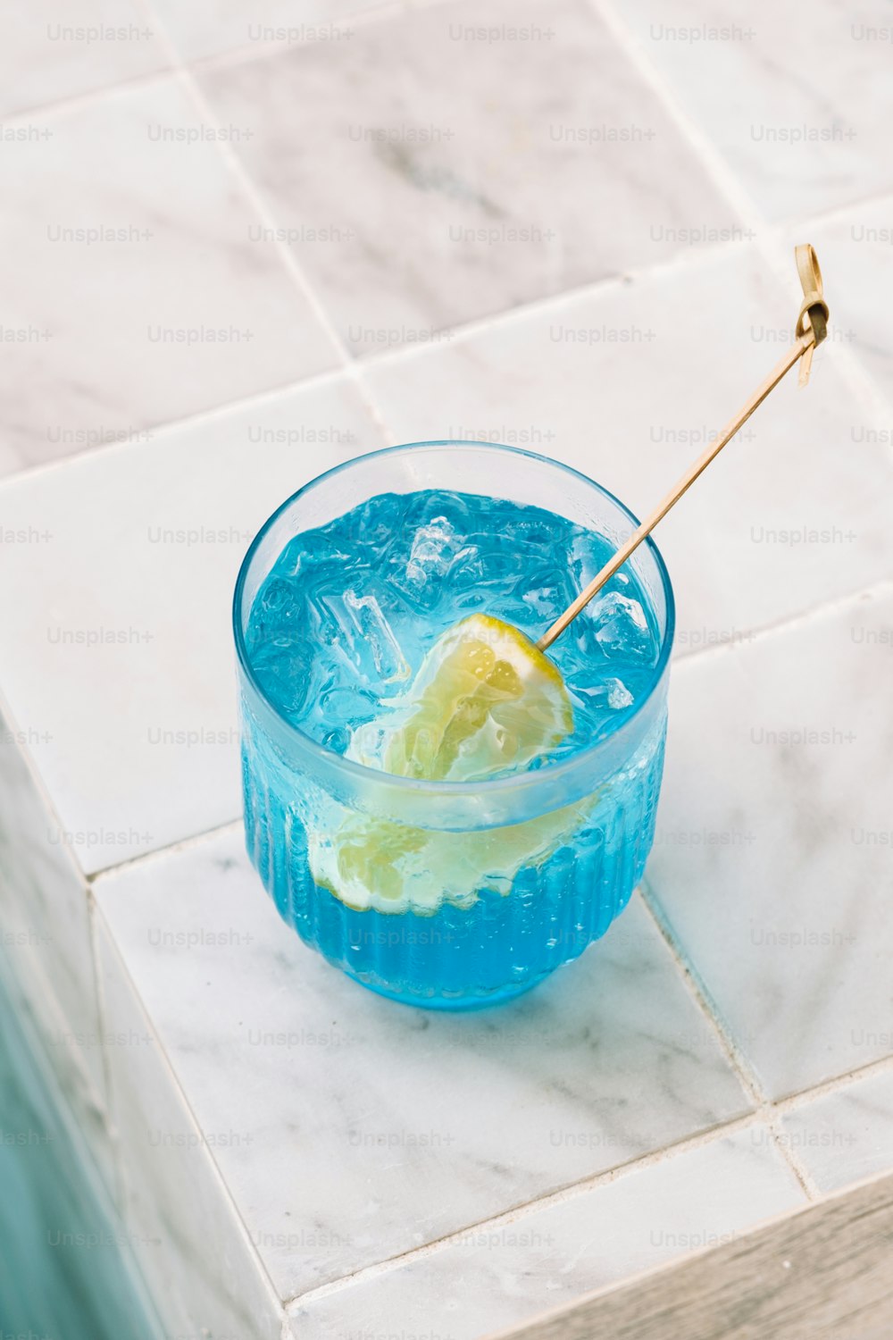 a blue drink with a lemon wedge in it