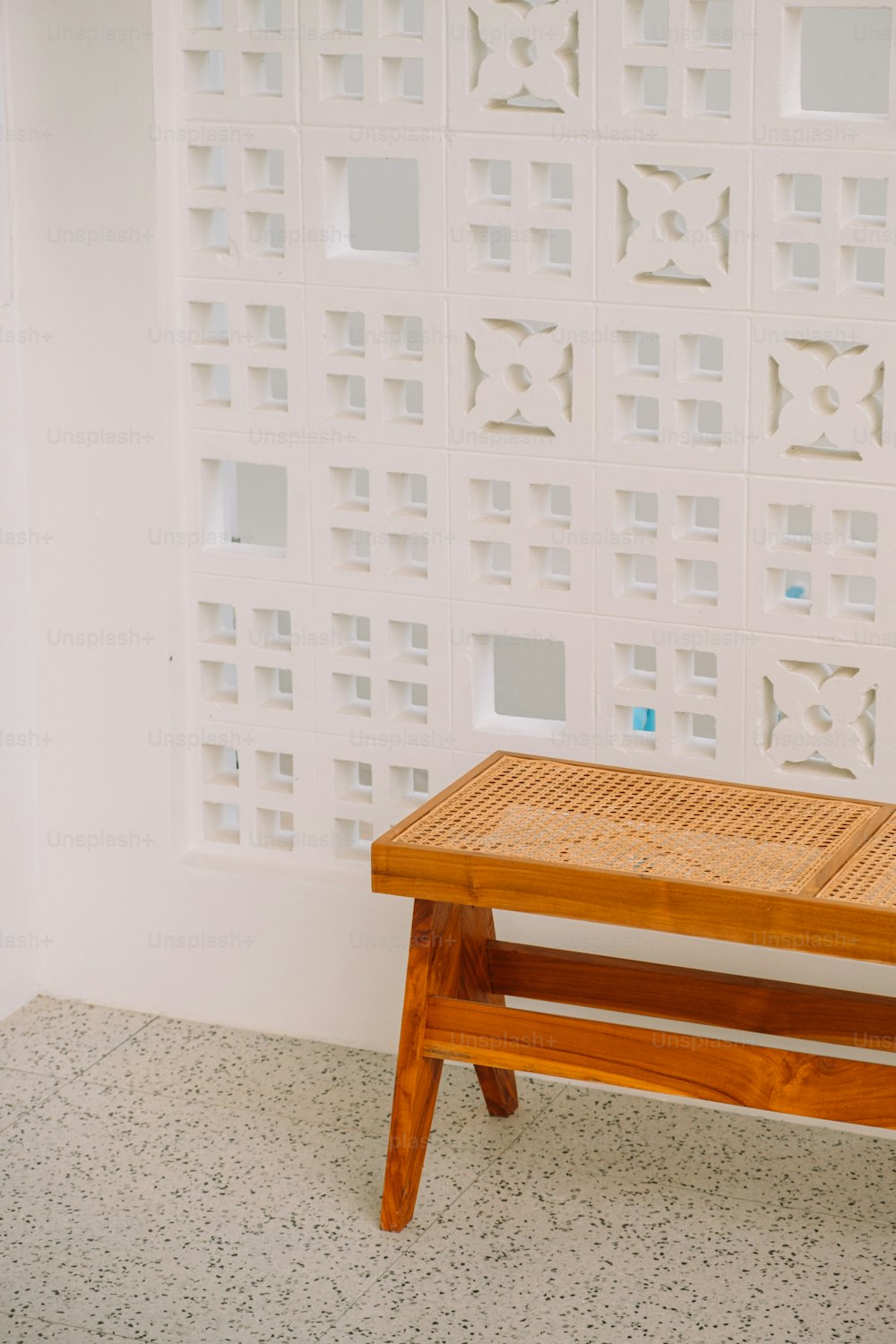 a wooden bench sitting in front of a white wall