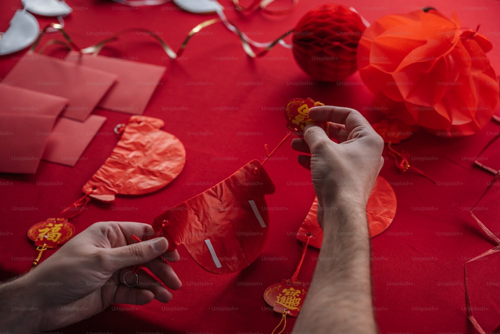 une personne faisant un cœur en papier sur une table rouge