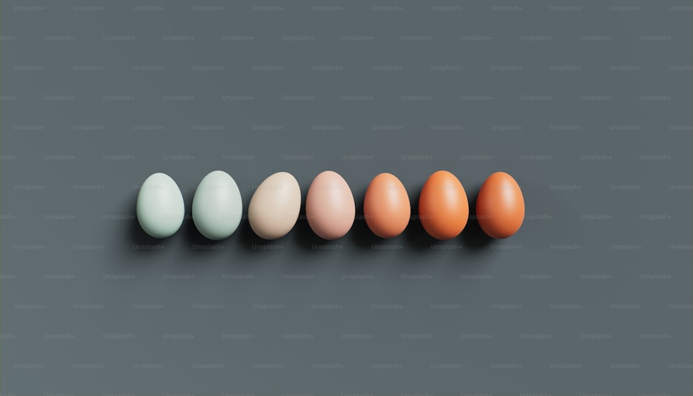 una fila de huevos de diferentes colores sobre un fondo gris