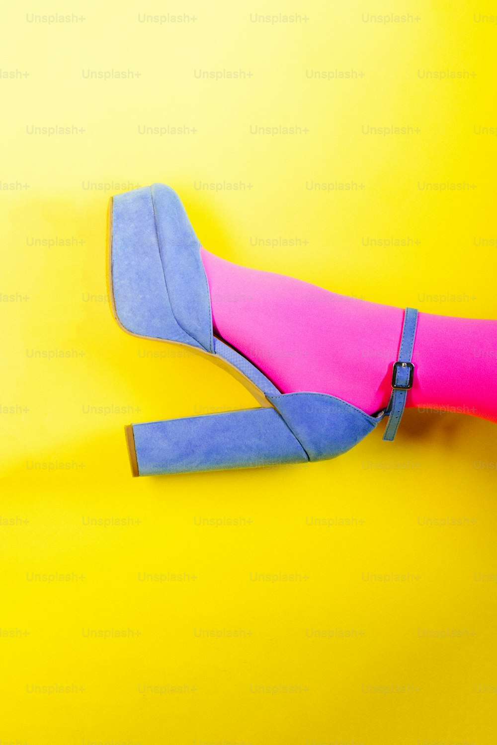 a pair of blue and pink shoes on a yellow background