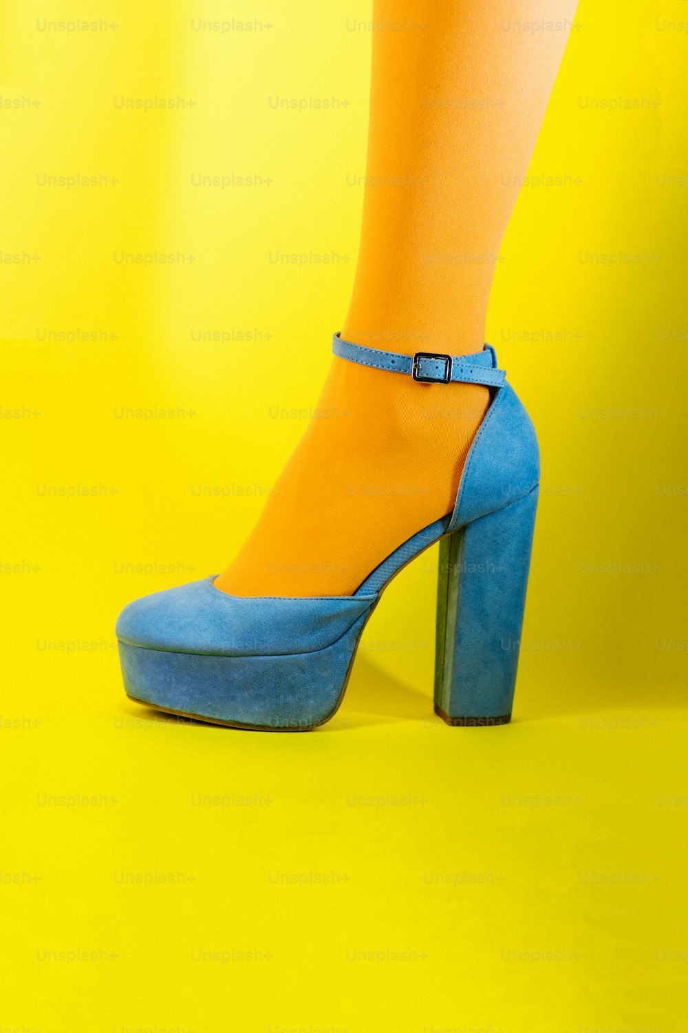 Die Beine einer Frau tragen blaue und gelbe High Heels
