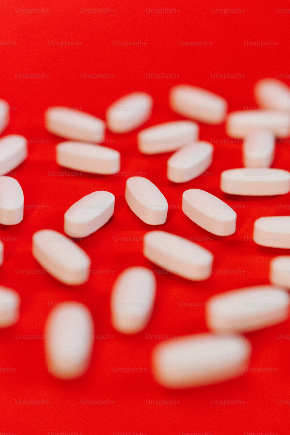 a close up of white pills on a red surface