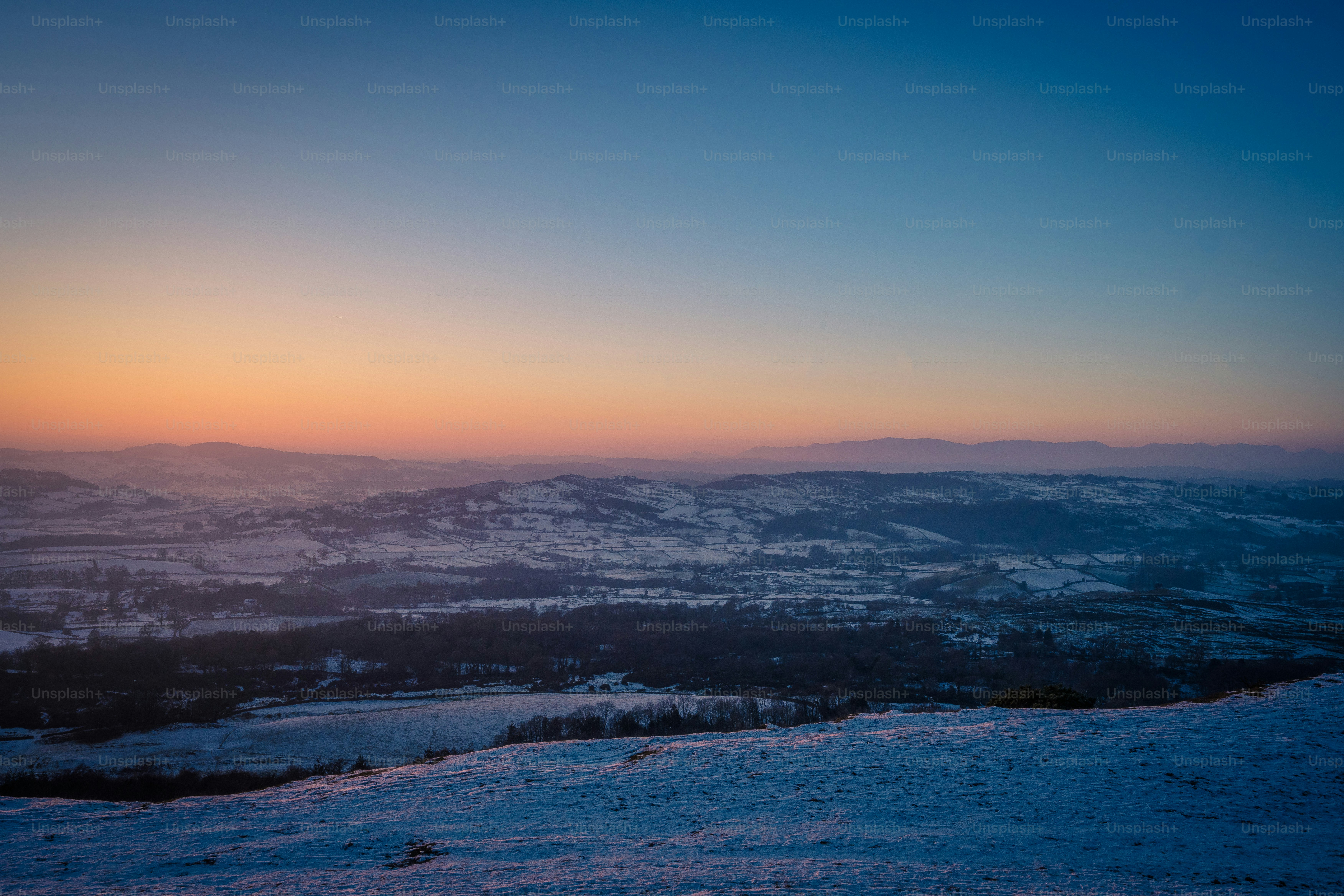 Die Sonne geht über einer verschneiten Landschaft unter