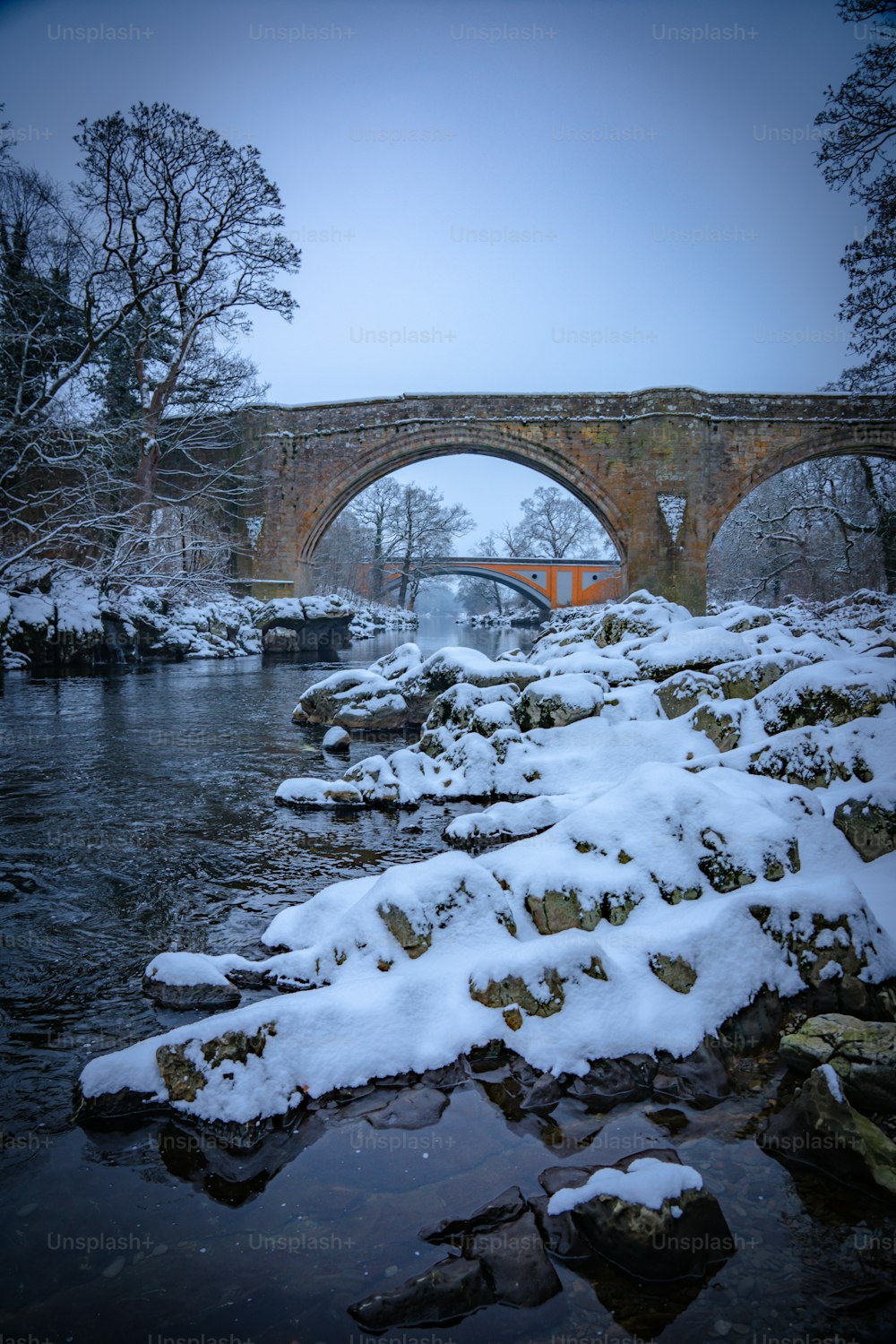 Un puente sobre un río con nieve en el suelo
