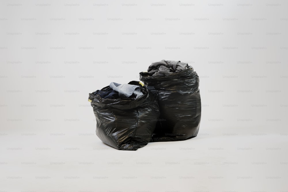 Un par de bolsas de basura sentadas encima de un piso blanco