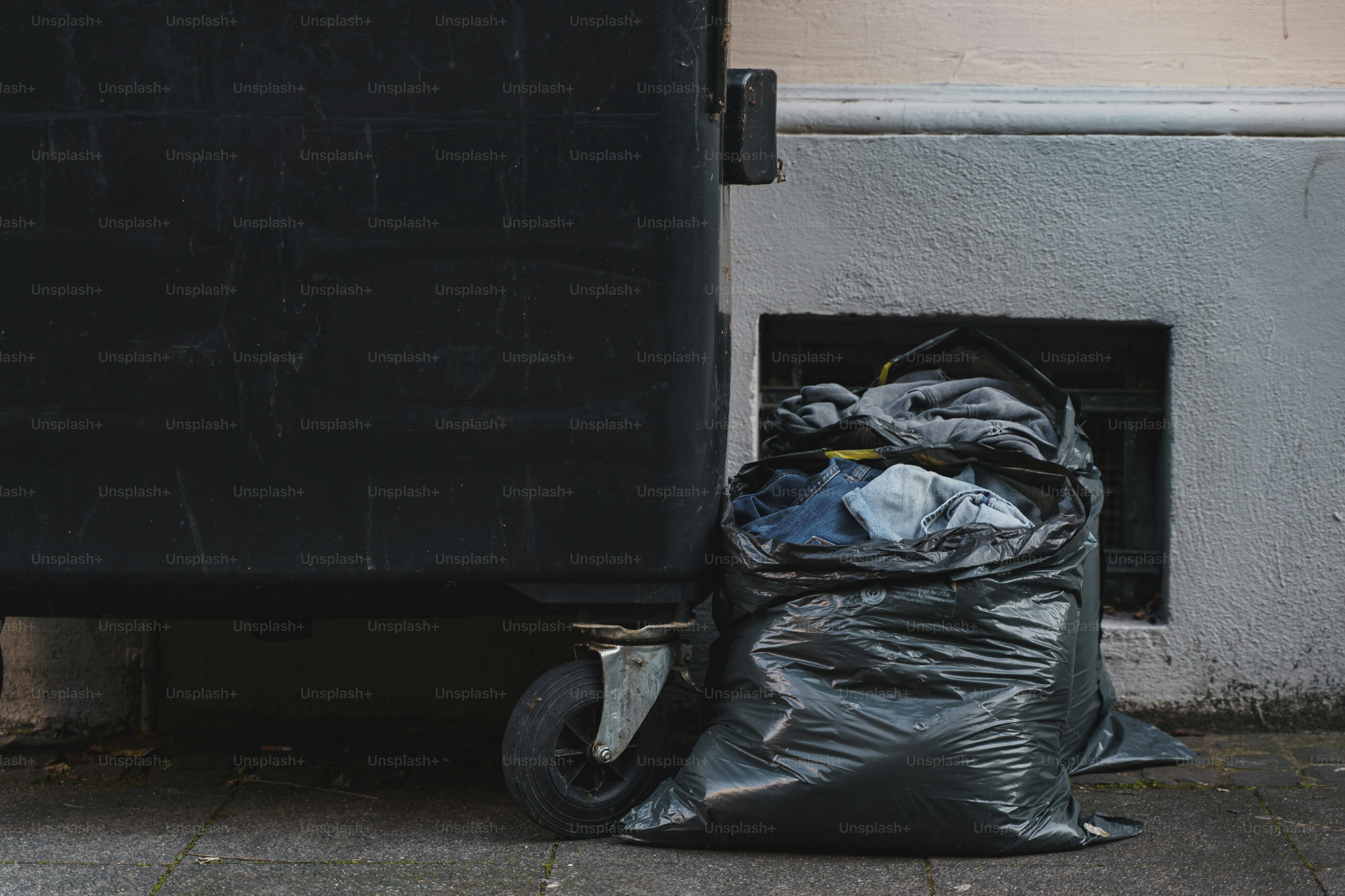 Fast Fashion symbolic pic: Clothes in a trashbag next to a trash bin..