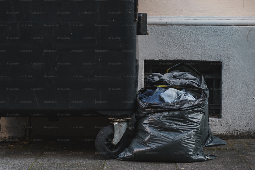 Una bolsa de basura sentada al lado de un bote de basura