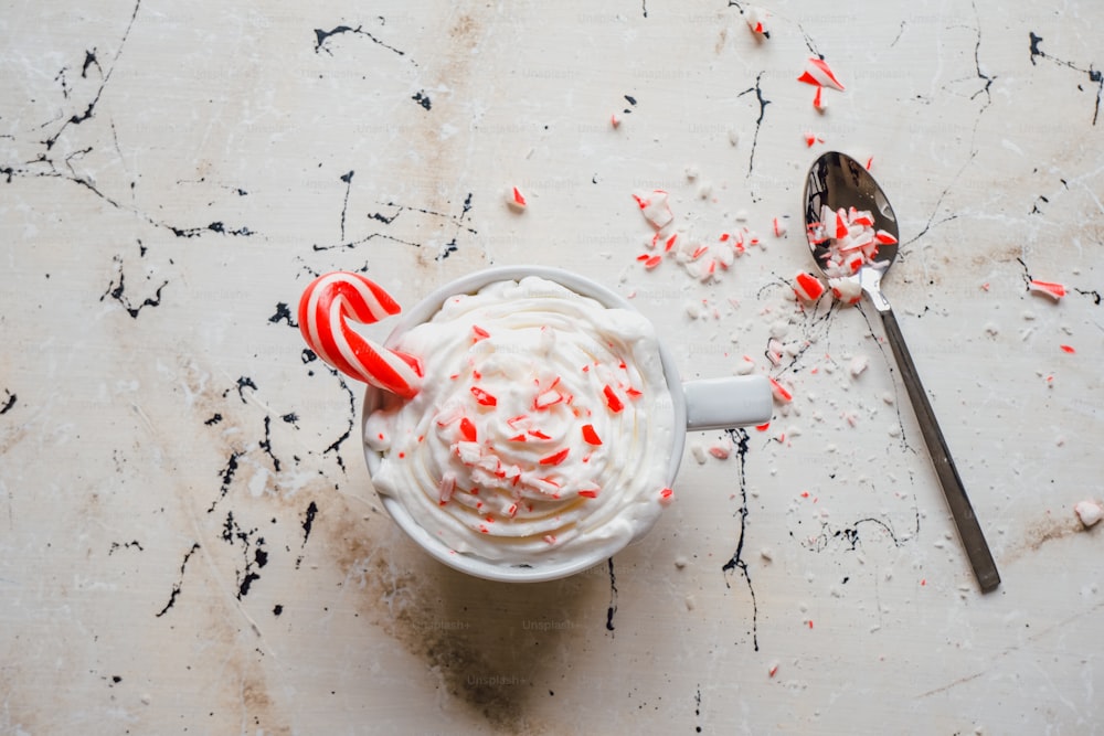 a cup of ice cream with candy canes on a table