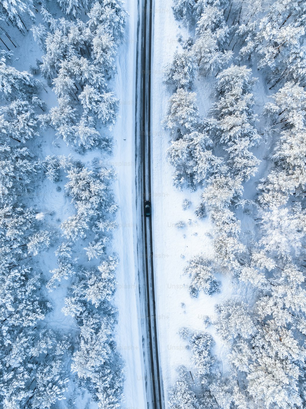 uma vista aérea de uma estrada no meio de uma floresta nevada