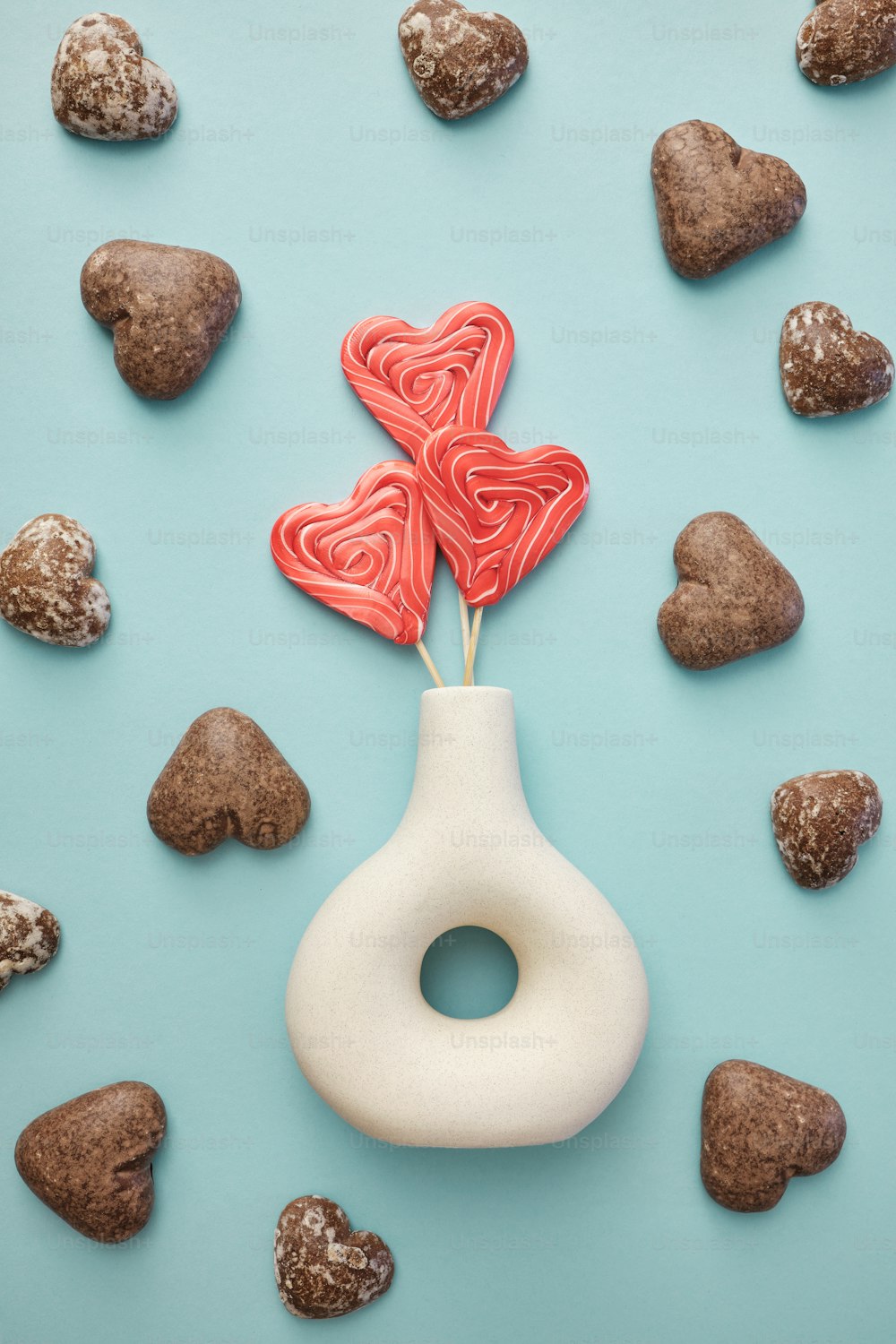 a heart shaped lollipop in a vase surrounded by rocks