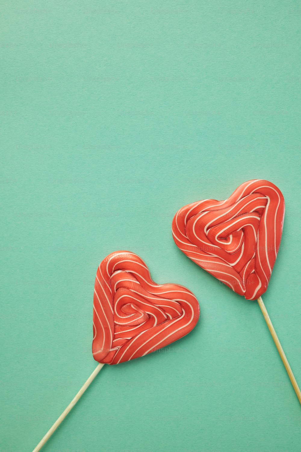 two lollipops shaped like hearts on a green background