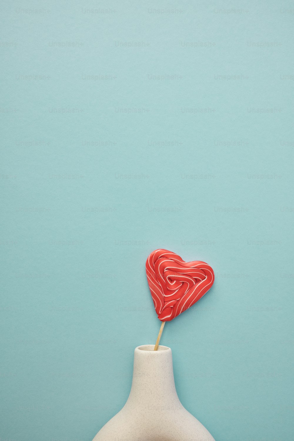 a heart shaped lollipop on a stick in a vase