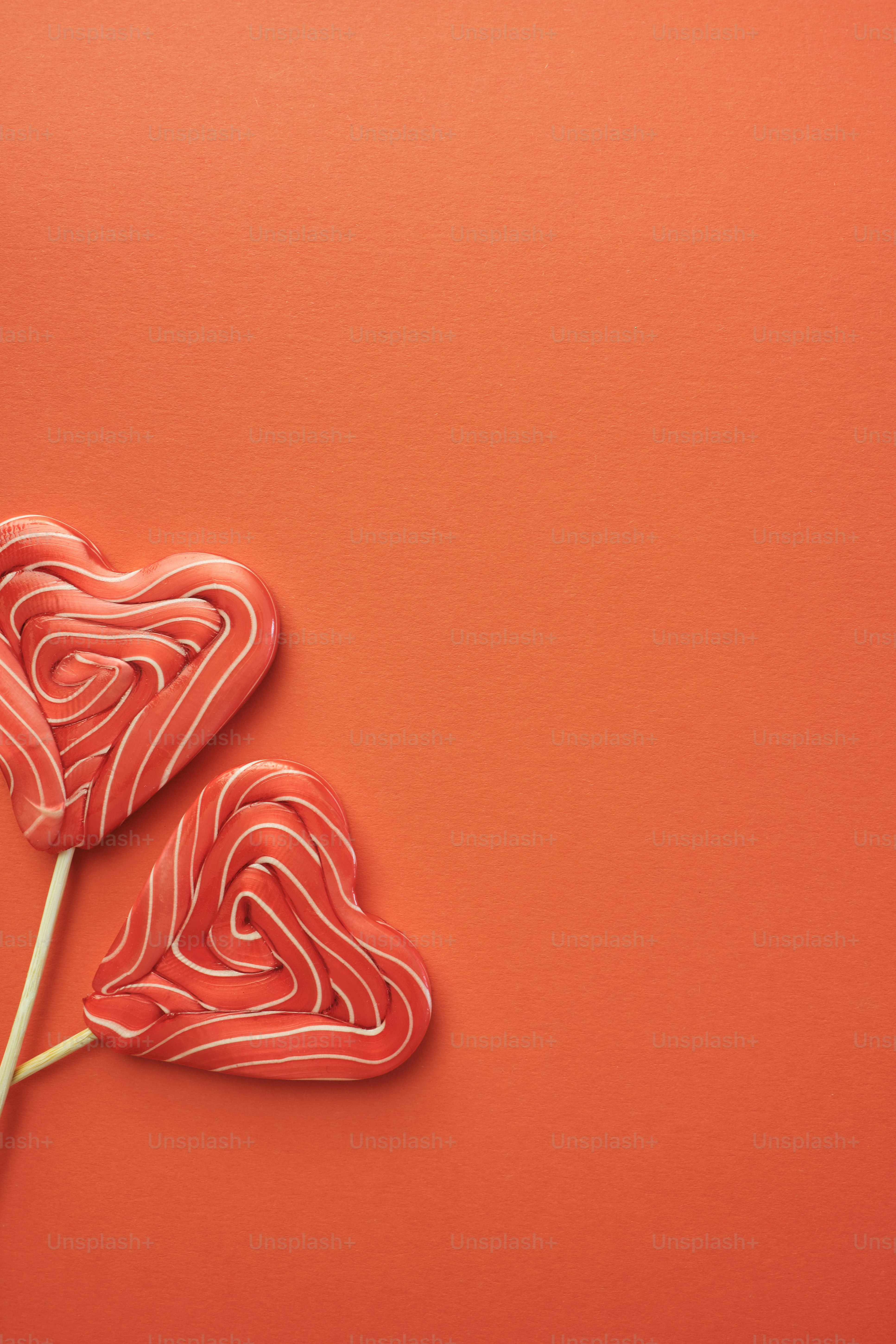 zwei herzförmige Lutscher auf rotem Grund