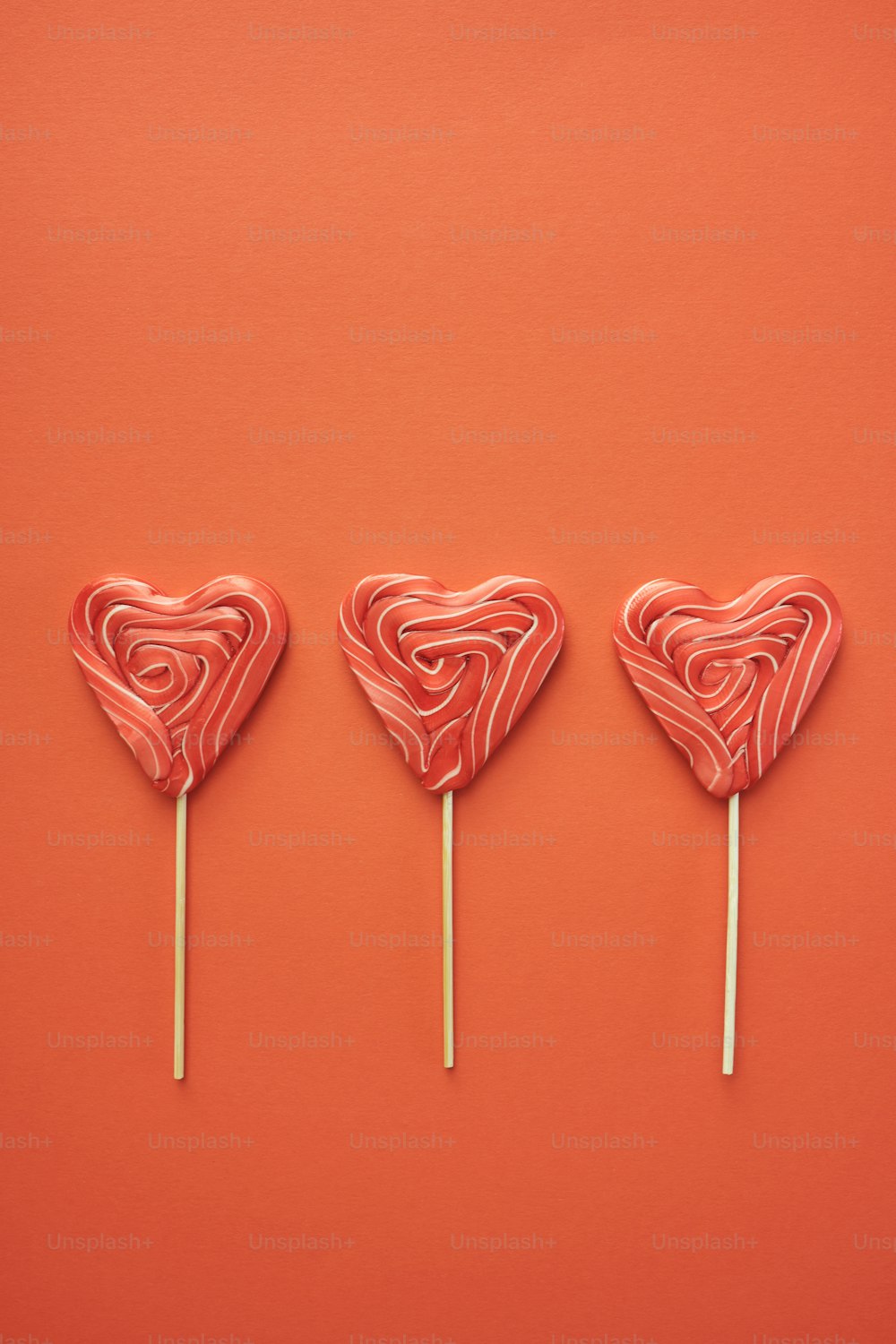 three lollipops shaped like hearts on a stick