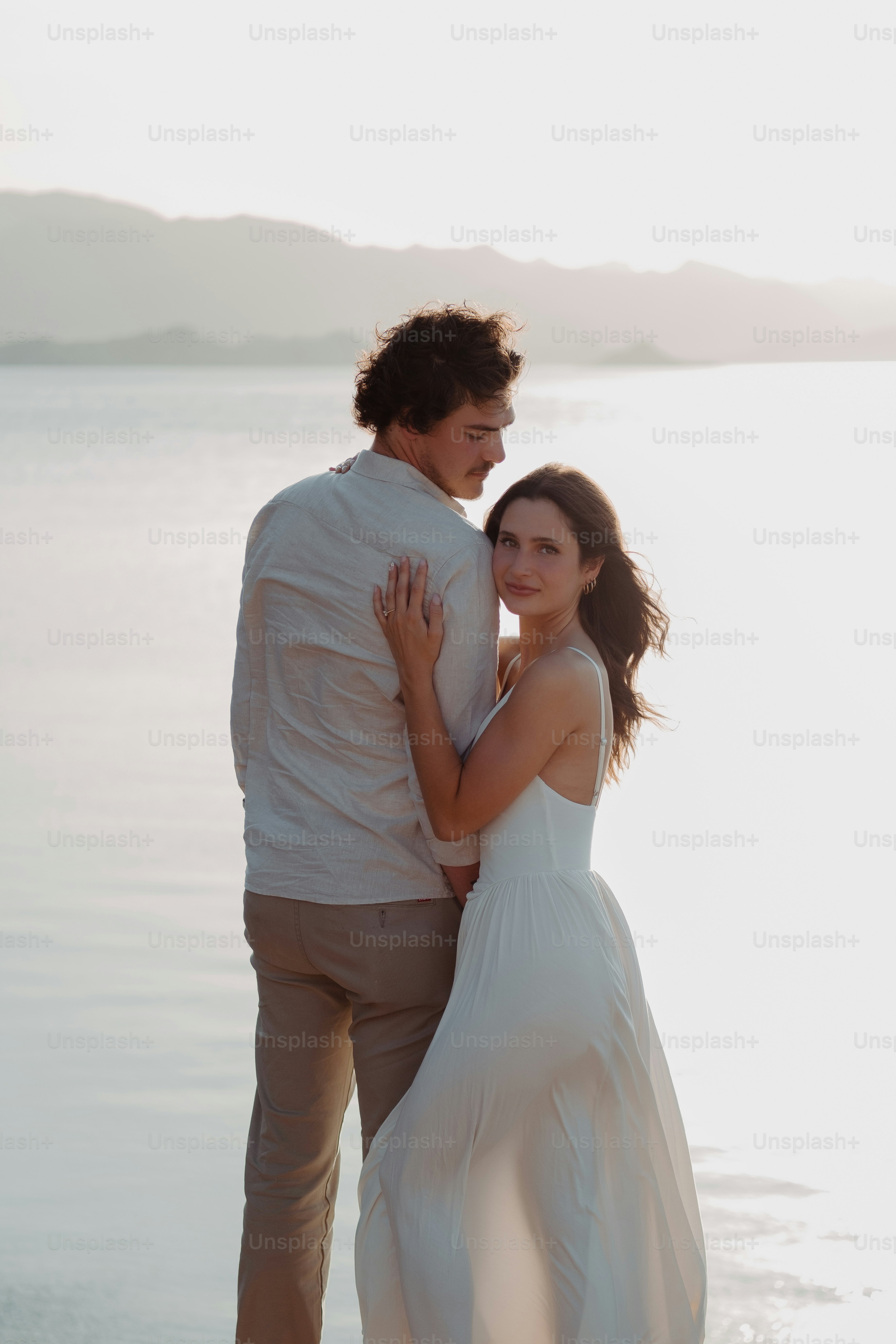 a man and a woman standing next to each other on a beach